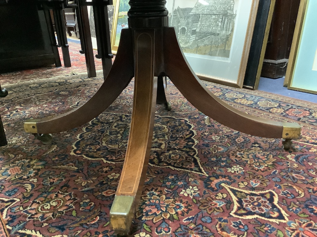 A late Georgian inlaid mahogany pedestal Pembroke table,on quadripartite splayed supports with brass castors, width 92cm depth 52cm height 70cm